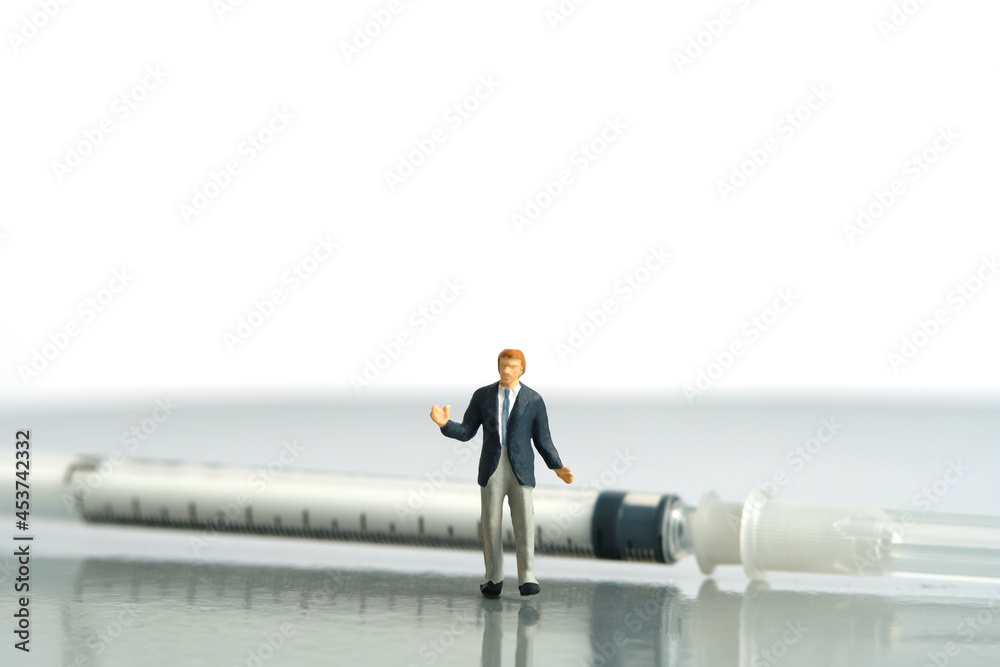 Miniature people toy figure photography. Hesitation on vaccination concept. A shrugging businessman standing in front of syringe vaccine. Isolated on white background