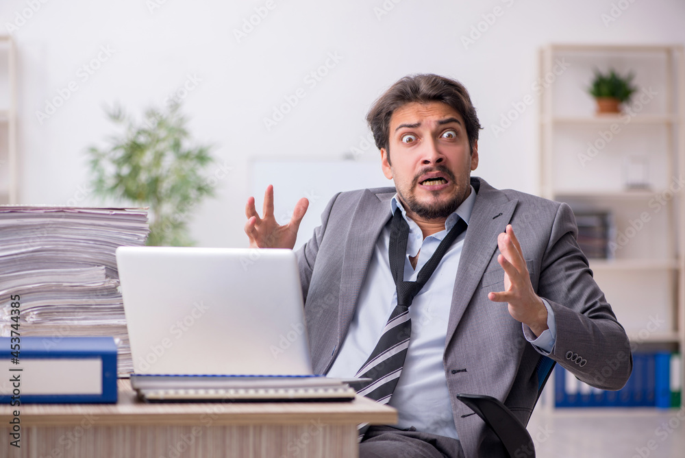 Young male employee and too much work in the office Young male employee and too much work in the office