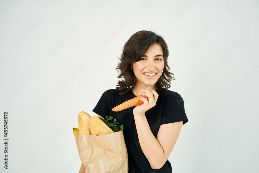 cheerful brunette in a black t-shirt with a package of products carrots in the hands of vegetables cheerful brunette in a black t-shirt with a package of products carrots in the hands of vegetables