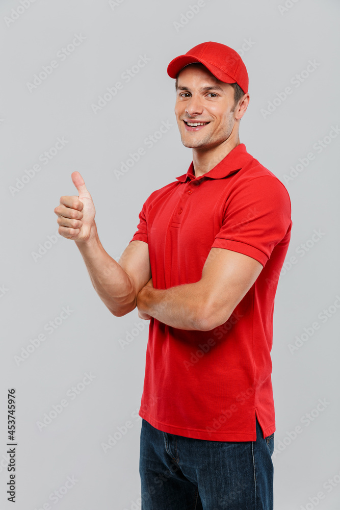 Young delivery man wearing uniform smiling while gesturing thumb up