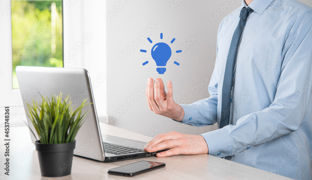 Businessman in a suit with a light bulb in his hands. Holds a glowing idea icon in his hand. With a place for text Businessman in a suit with a light bulb in his hands. Holds a glowing idea icon in his hand. With a place for text