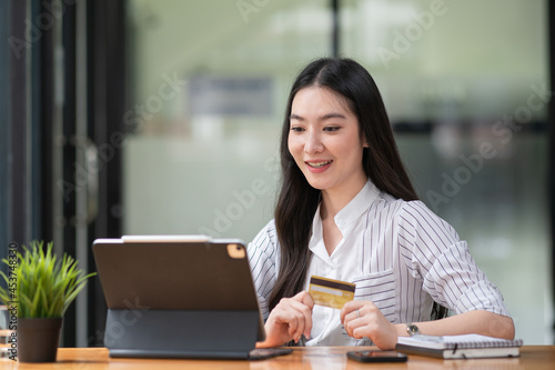 Young woman holding credit card and using a laptop computer. Online shopping concept