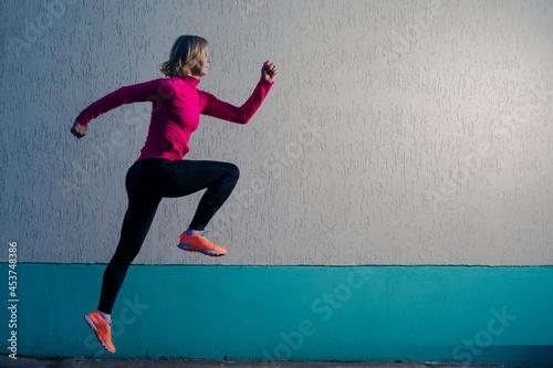 Concentrated Running Mature Sportswoman Having Outdoor Jogging Training Against Concrete Wall Background.