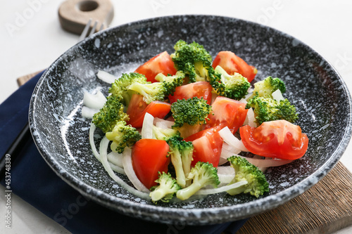 Plate of tasty salad with broccoli on light background