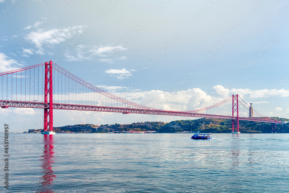Fototapeta premium Portugal Travel Ideas. One Blue Sailing Boat With Group of Tourist on Tagus River Under 25th of April Bridge in Lisbon
