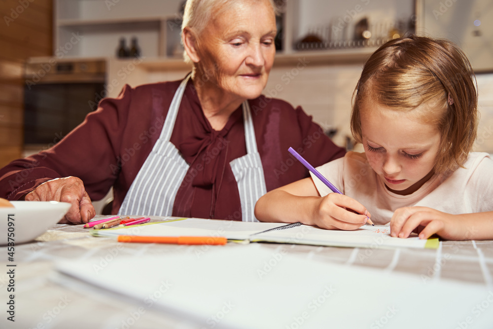Girl using purple pencil while drawing with elderly woman Girl using purple pencil while drawing with elderly woman