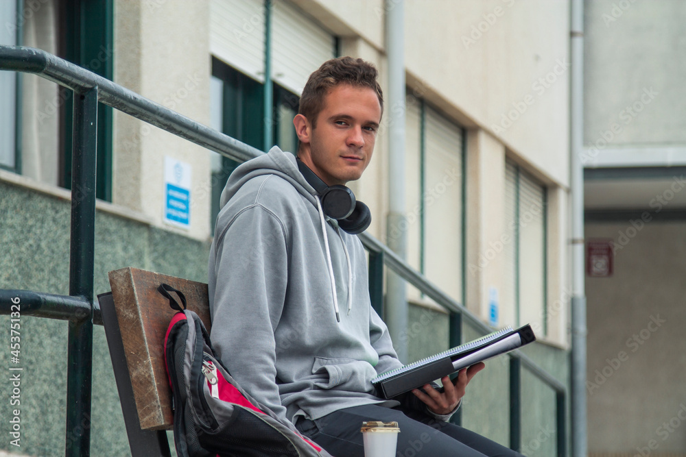 young student with headphones sitting in front of institute or university young student with headphones sitting in front of institute or university