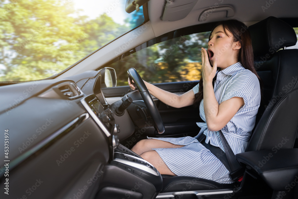 tired woman yawning and sleepy while driving car