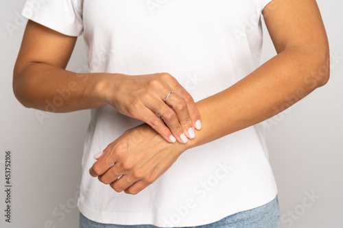 Woman holding fingers on wrist checking pulse. Tired female touching arm to measure heart beat or blood pressure, massages wrist after working at computer, pressing vein with hand. Arthritis concept.