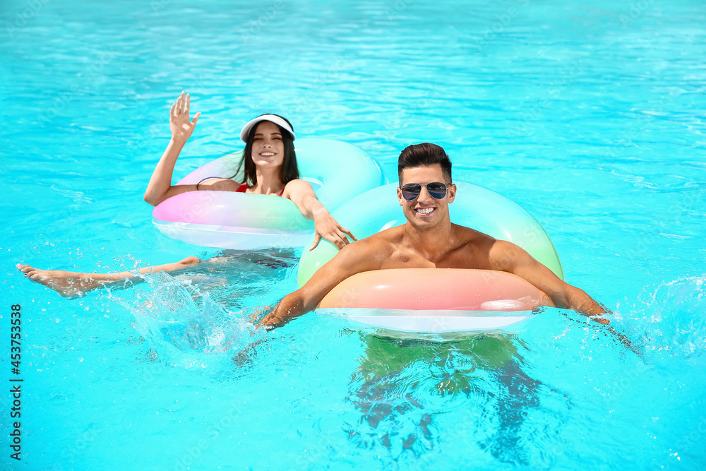 Young couple with inflatable rings in swimming pool Young couple with inflatable rings in swimming pool