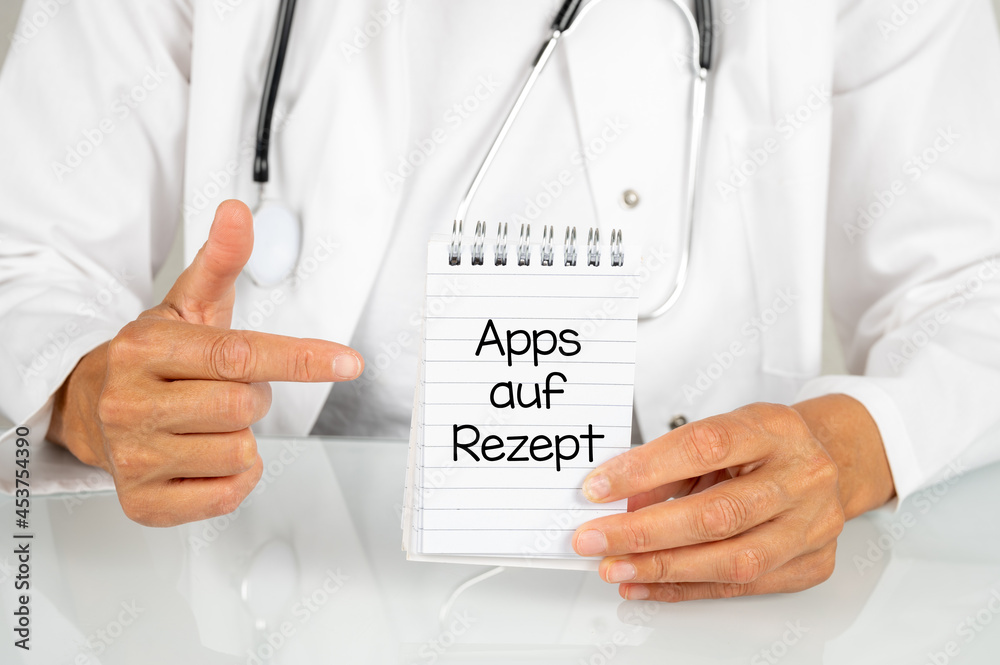 Ärztin zeigt mit dem Finger auf einen Notizblock auf dem Apps auf Rezept steht Ärztin zeigt mit dem Finger auf einen Notizblock auf dem Apps auf Rezept steht