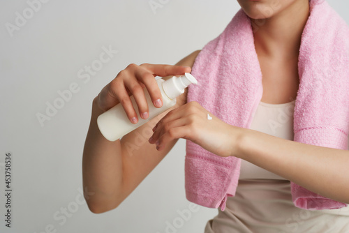 woman with pink towel applies lotion on hand body care