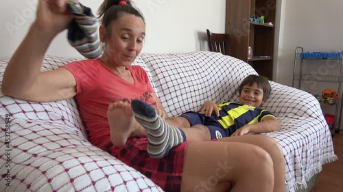 4K Playful mother takes off socks of boy resting on sofa and tickles him
 photo