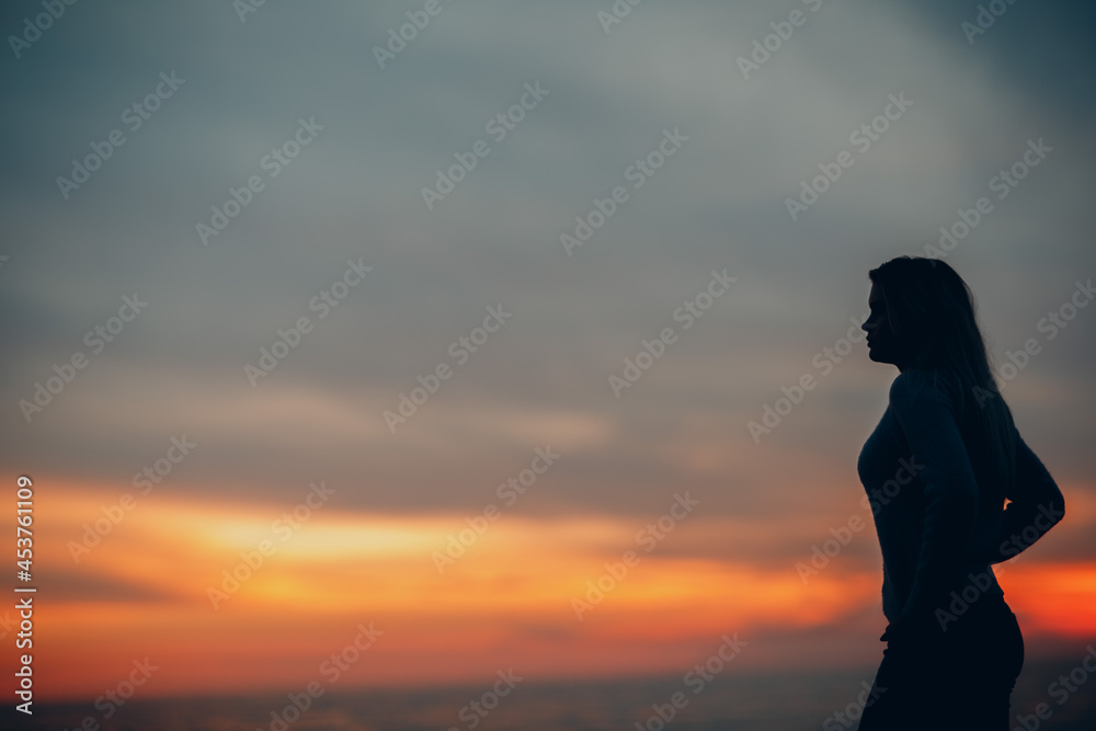 Young woman silhouette on the seashore pebble beach