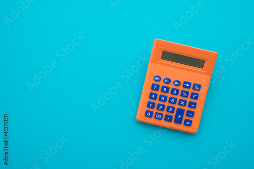 Accounting, tax, banking, business and financial concept. Flat lay or top view of orange calculator on blue table background with blank copy space.