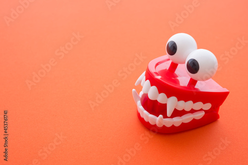 Fotografija Vampire chattering teeth toy on red background with copy space
