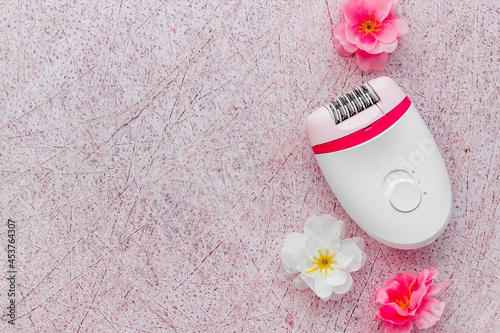 Epilator with pink and white flowers. Hair removal and depilatory concept photo