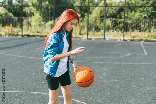A beautiful teenage girl leads a basketball on a sports field, a girl learns to play basketball