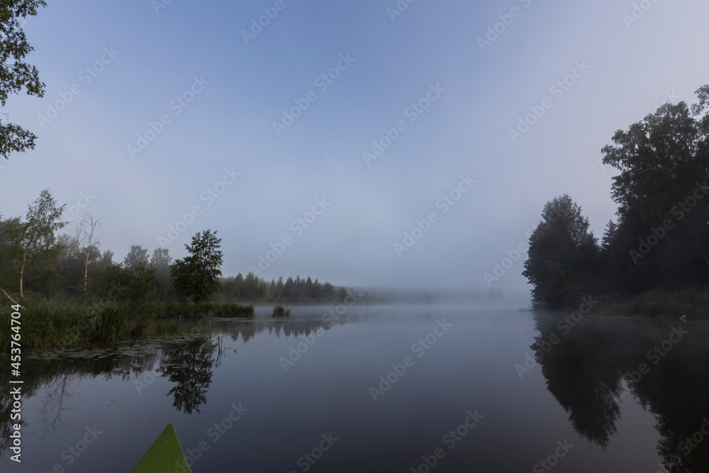 Mystical landscape at dawn. Early morning. Fog on the river. Beautiful dawn in the summer by the river. View from the boat to the morning landscape.