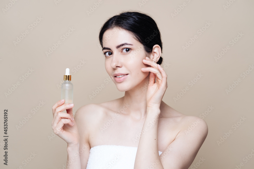 Woman holds hyaluronic serum. Photo of pretty woman with perfect skin on beige background. Beauty product presentation
