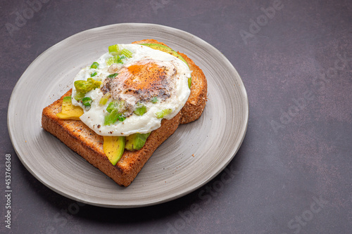 Toast with avocado and eggs served on a plate on vintage background. Top view. Space for text