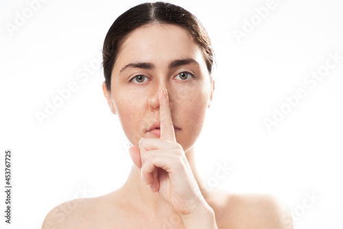 Plastic nose surgery. Portrait of young caucasian woman touching her crooked nose isolated on white background. Concept of rhinoplasty