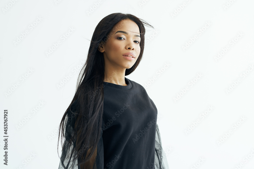 Fototapeta premium beautiful fashionable woman of african appearance dark shirt long hair light background