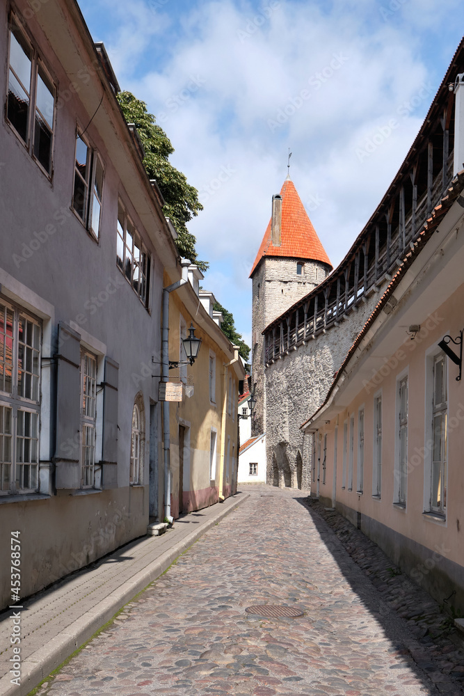 Tallinn, Estonia, ancient architecture. Old traditional houses by town Wall with Tower. European medieval fortifications. Traditional Baltic architecture.Bright summer day, nobody around..