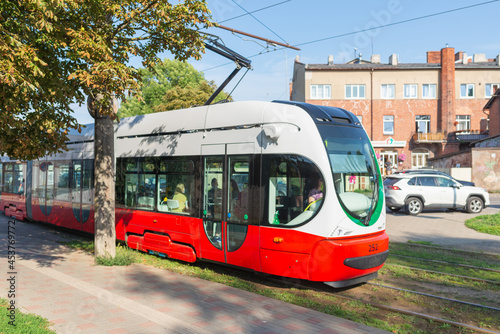 Traditional old tram in the Town. Red and white tram in a city.Contemporary railway transport city in summer.