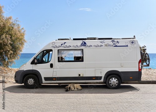 Fototapeta Naklejka Na Ścianę i Meble -  Motorhome is parked near sea beach. The owners left, leaving the dog to guard the van.