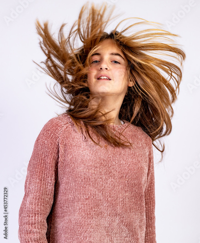 Young smiling girl shaking her head with hair dishevelled by the wind in a glamorous pose