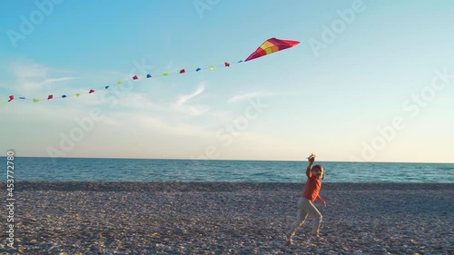 Happy Kid runs with kites along the sea line. children playing with a kite at sea. family vacation concept with children at sea