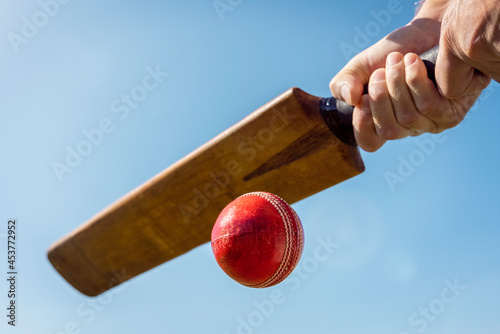 Photography Cricket player batsman hitting a ball with a bat shot from below background
