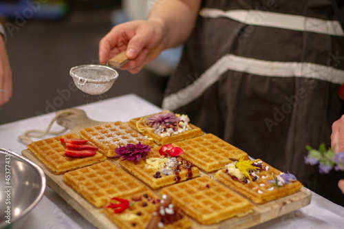 decorated waffles getting prepared to be cooked on a wooden board with blurred background