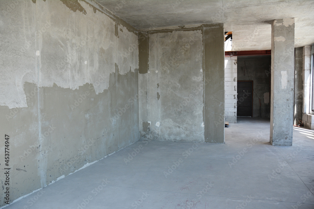 Apartment renovation of a newly built house with concrete floor, finishing on walls, and a concrete column, or pillar.