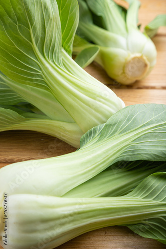 Fresh green bok choy or pac choi chinese cabbage on a brown wooden background. Side view.