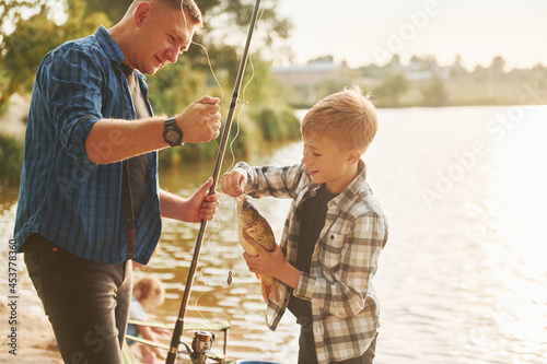 Showing the catch. Father and son on fishing together outdoors at summertime