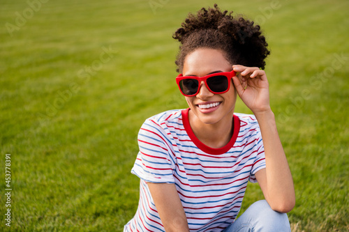 Photo of young attractive african woman happy positive smile hand touch sunglass grass summer outdoors