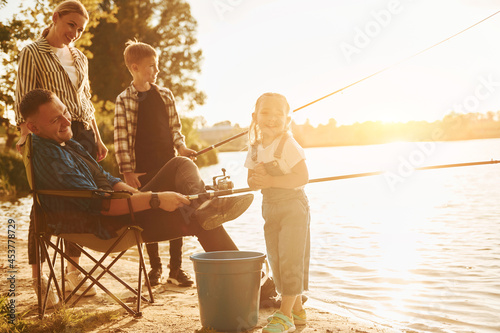 Beautiful nature. Father and mother with son and daughter on fishing together outdoors at summertime