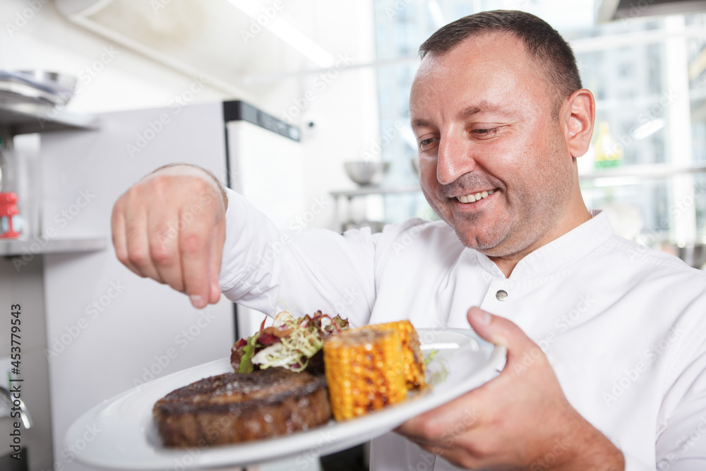 Professional chef preparing delicious beef steak with salad and sweet corn dish