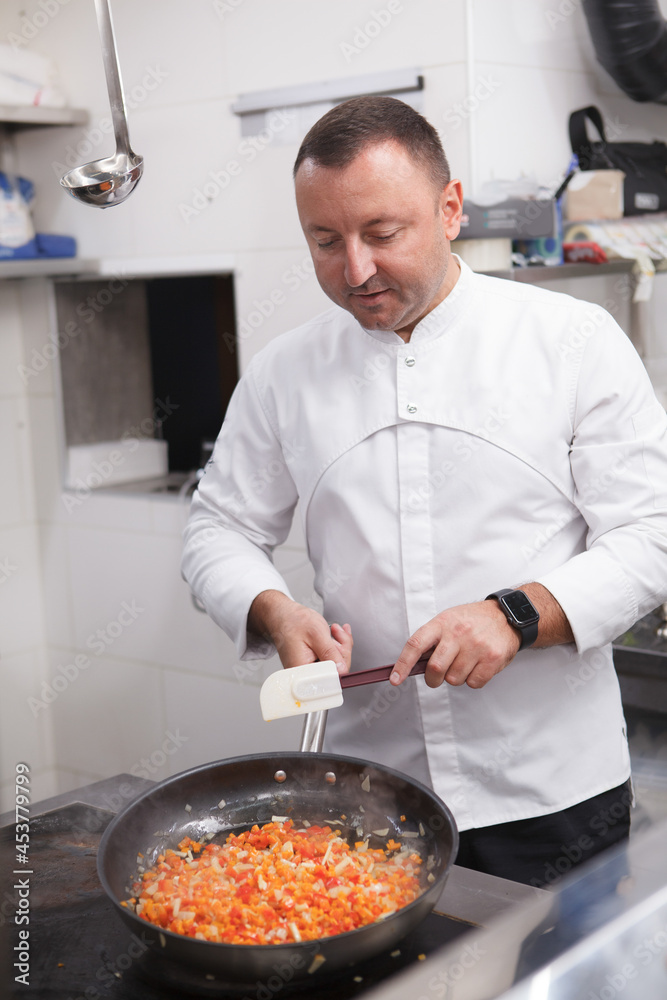 Vertical shot of a restaurant chef preparing fried vegetables