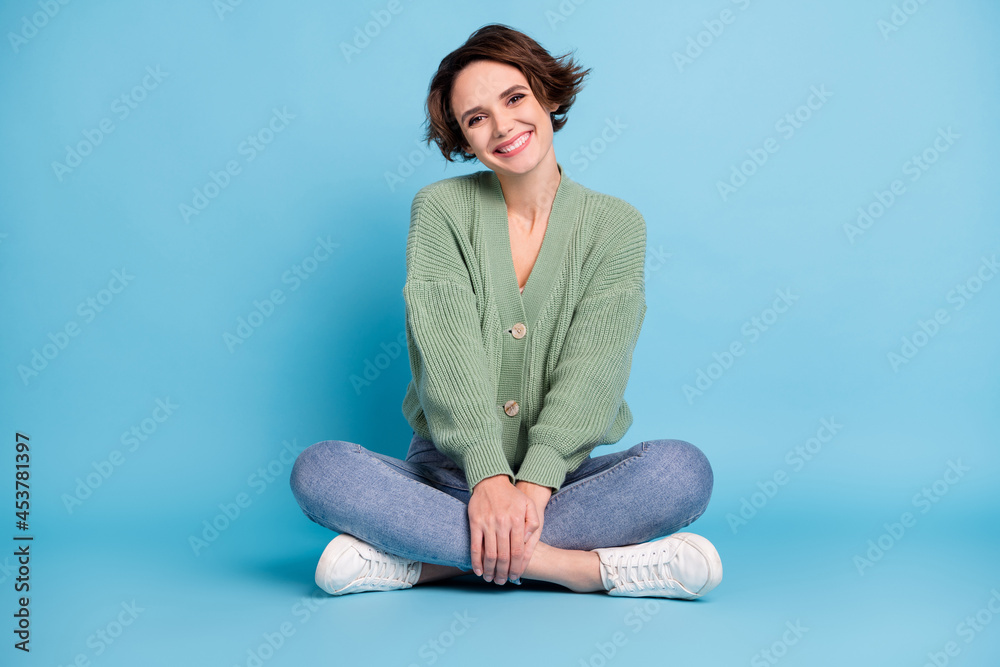 Photo of sweet charming young woman wear green cardigan sitting legs folded isolated blue color background