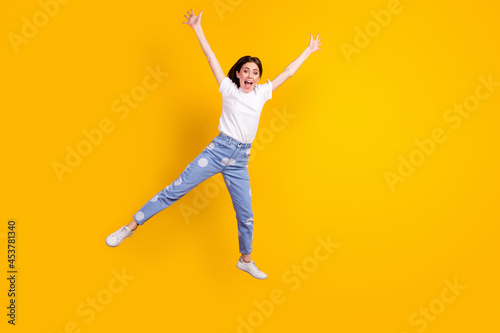 Full body photo of young excited girl happy positive smile jump up isolated over yellow color background