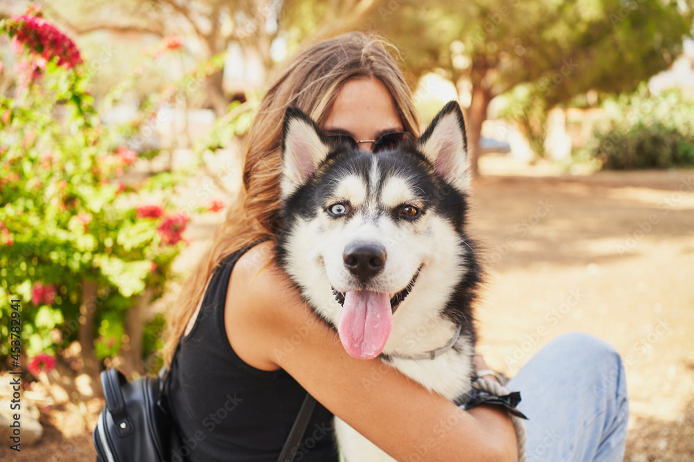 Unrecognizable woman behind her siberian husky who looks at camera