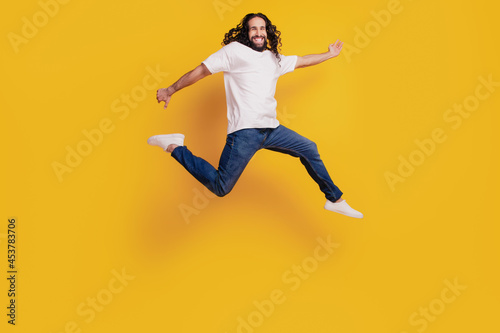 Portrait of active crazy funky guy run fast hurry jump on yellow background © Tetiana