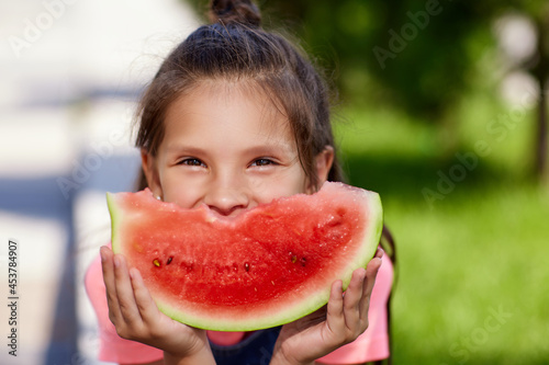 child girl eats a watermelon in sunny day