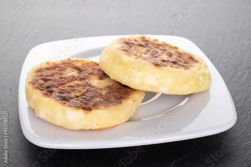 Two fragrant homemade cheesecakes with ceramic dishes on a slate stone, close-up, isolated on white.