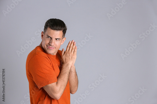 Obraz na plátně Greedy man rubbing hands on grey background, space for text