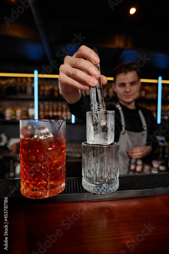 Barman puts the ice cubes into a glass