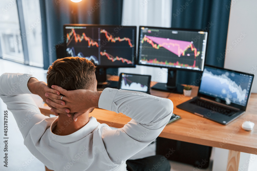 Taking a rest. Young businessman in formal clothes is in office with multiple screens Taking a rest. Young businessman in formal clothes is in office with multiple screens